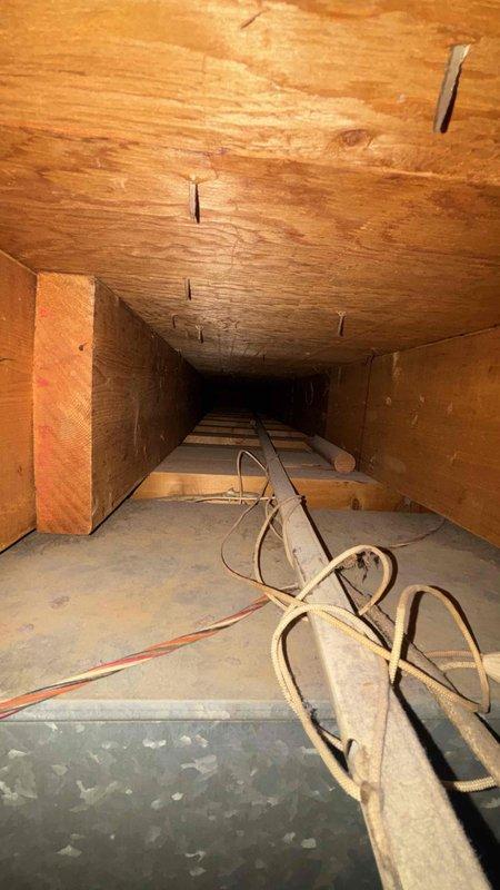 Conducted comprehensive assessment of existing basement cooling system for residential property sized between 1001-1599 square feet to provide replacement estimate. Evaluated current unit configuration, ductwork infrastructure, and installation accessibility in confined crawl space area with exposed structural elements. Documented existing HVAC system conditions including flexible duct routing, electrical connections, and clearance requirements for equipment replacement. Photographed installation site showing spray foam insulation, metal piping runs, and available workspace for new equipment installation to ensure proper sizing and configuration recommendations for replacement cooling system.
