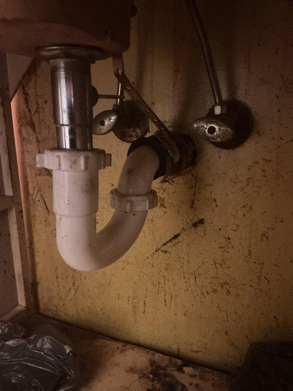 Responded to bathroom sink clog complaint and successfully cleared the drain obstruction. Upon inspection, found standard P-trap configuration with chrome two-handle faucet assembly; noted aging fixtures with visible corrosion on supply valves and general wear throughout plumbing components. Restored proper drainage function and completed service.