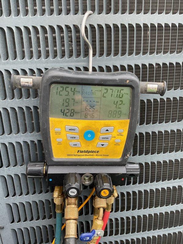 # HVAC Service Completed

Responded to service call for 5-year-old air conditioning system with inoperative fan and complete loss of heating and cooling capability. Upon arrival, performed visual inspection and diagnostic testing of outdoor condensing unit.

Identified failed contactor as primary issue preventing compressor and condenser fan operation. Contactor showed signs of electrical failure with burned or pitted contacts preventing proper circuit closure. Verified all wire connections at contactor terminals for proper seating and condition, noting multiple color-coded wires including line voltage and control circuit wiring.

Utilized Fieldpiece SMAN digital manifold gauge set to assess system pressures and temperatures. Connected refrigerant hoses to service ports and recorded operating parameters. Display readings indicated abnormal pressure conditions consistent with non-operational compressor. Monitored both high-side and low-side pressures along with corresponding saturation 