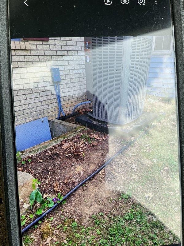 Performed follow-up service call to address continuous fan operation issue on outdoor HVAC condensing unit. Conducted system inspection and documented equipment condition with site photographs showing unit positioned on concrete pad against exterior wall with electrical conduit and refrigerant line connections visible. Addressed outstanding work items from previous installation to resolve fan control malfunction.