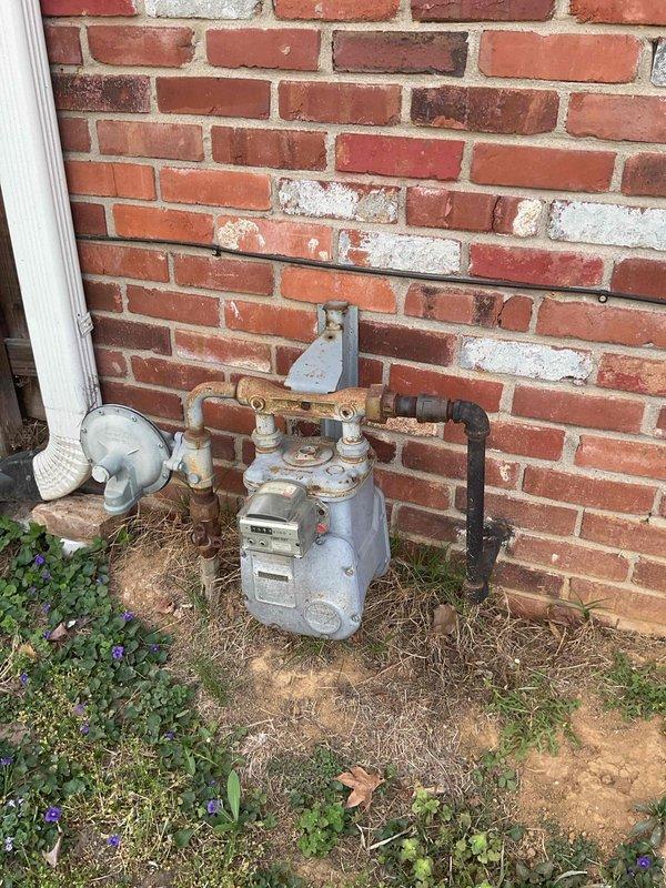 Conducted comprehensive replacement estimate for residential HVAC system including non-operational gas furnace from early 2000s and 2013 air conditioning unit. Assessed existing outdoor AC unit with cylindrical configuration, electrical disconnect, and PVC condensate drainage, along with gas meter infrastructure and utility connections at brick foundation. Documented current equipment condition, measured installation space requirements, evaluated electrical service capacity, and provided complete system replacement recommendations for both heating and cooling components.