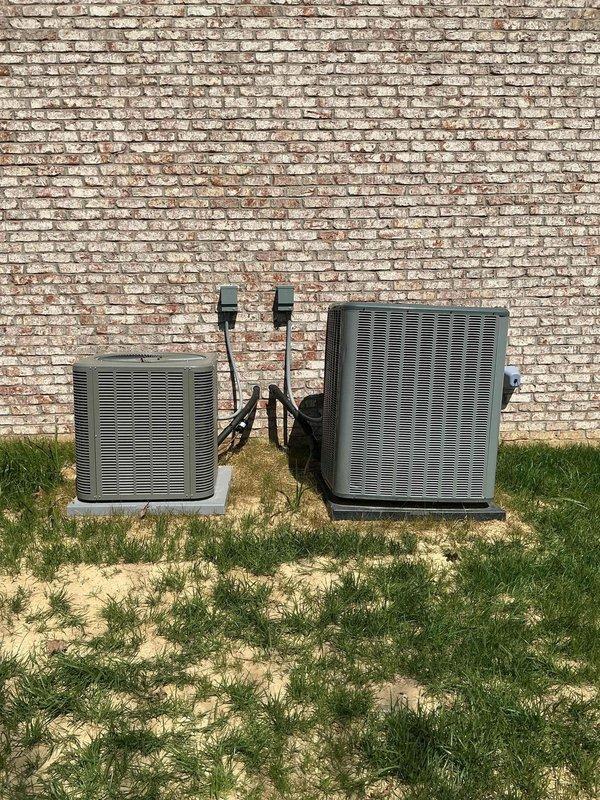 Responded to customer concern regarding unlevel outdoor condensing units affecting system performance. Upon arrival, inspected two HVAC condensing units installed side by side on shared concrete pad at exterior brick wall. Visual assessment confirmed units were not properly leveled on pad, which can lead to compressor strain, refrigerant migration issues, and premature equipment failure. Verified electrical disconnects and conduit connections were secure between wall-mounted junction boxes and both units. Documented current installation conditions with photographs showing unit positioning, concrete pad settlement, and surrounding grade conditions for service records.