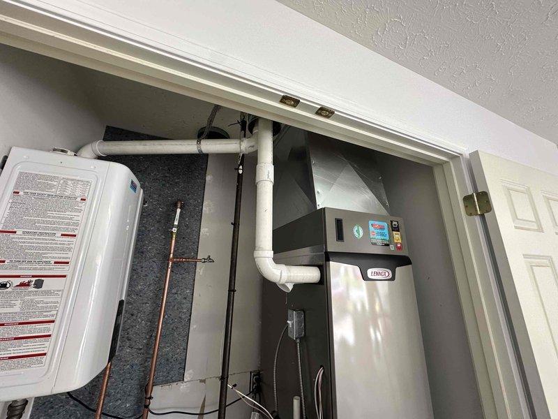 Completed full HVAC system installation including a 3-ton Lennox unit with 23.5 SEER rating and 99% efficiency furnace, mounted in utility closet with proper ventilation and clearances. Installed powered humidifier integrated with new system, ran white PVC condensate drainage lines with appropriate pitch and connections, and added supply ventilation ductwork. Water heater was relocated and reconnected with copper supply lines and PVC venting to accommodate new HVAC equipment placement. All components secured with proper mounting brackets, piping labeled and routed efficiently through mechanical space, and system tested for proper operation and airflow.