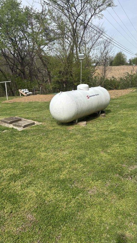 Conducted comprehensive HVAC replacement estimate for residential property with 29-year-old existing system. Evaluated outdoor condensing unit with protective cage guard positioned on concrete pad against building exterior, assessed refrigerant line routing and electrical connections, and documented propane tank location on property for system planning considerations. Homeowner requested full replacement options only with no repair alternatives.