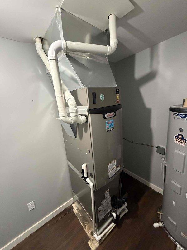 Completed full HVAC system installation featuring a 3-ton, 17 SEER, two-stage heat pump paired with a 97% AFUE two-stage gas furnace in an indoor utility closet. Installed vertical furnace unit with proper venting configuration using white PVC piping routed through ceiling with multiple elbows and joints for intake and exhaust. Connected refrigerant lines between indoor air handler and outdoor condensing unit using copper linesets with proper insulation and wall penetration sealing. Installed condensate drainage system with PVC piping and condensate pump at base of furnace to handle moisture removal. Secured all refrigerant lines to wall with appropriate mounting clips and brackets. Completed all electrical connections, tested system operation in both heating and cooling modes, verified proper airflow and refrigerant charge levels, and confirmed two-stage functionality is operating as designed for optimal efficiency and comfort control.