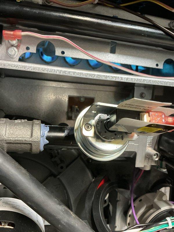 # HVAC Install - Complete System

Successfully completed full HVAC system installation featuring a Lennox furnace unit. The installation was performed in a utility area with proper clearances and professional workmanship throughout.

The furnace was mounted on a white platform base with adequate structural support. Galvanized sheet metal ductwork was installed above the unit to ensure proper airflow distribution. White PVC condensate drain piping was configured in a U-shaped trap on the left side of the furnace to facilitate proper drainage and prevent airflow issues.

Internal components were properly installed and verified, including the blue flame igniter assembly mounted on refractory board with appropriate electrical connections. Gas valve and pressure switch components were secured with proper fittings and connections. All electrical wiring was routed correctly throughout the system, including red, purple, and white conductor wires to burner assembly, blower motor, and control co