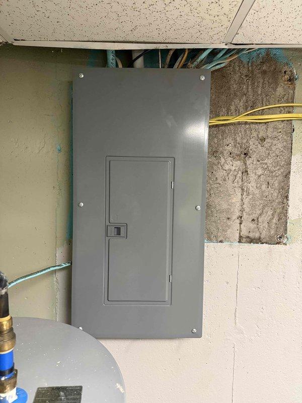 Completed electrical service upgrade including replacement of main electrical panel and utility meter. Installed new gray metal panel box in interior utility space with proper mounting and secure connections, ran necessary conduit and wiring from exterior meter location through building structure to new panel. Replaced exterior weathered meter assembly with updated equipment, ensuring proper weatherhead connections and conduit routing along brick exterior wall. Additionally replaced interior light fixture per customer request. All work completed to code with proper grounding and circuit protection, system tested and verified operational.