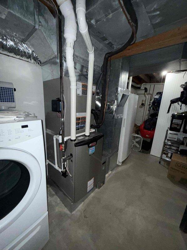 # HVAC Install - Complete System

Completed full HVAC system installation including 18 SEER heat pump outdoor unit and 99% AFUE gas furnace with air handler to serve main level and basement zones. Installed new furnace unit in basement mechanical room with proper clearances and ventilation requirements. Configured white PVC condensate drain lines with insulation wrap, routing vertically through ceiling joists to appropriate drainage location.

Connected silver flexible ductwork from furnace to existing distribution system, ensuring proper sealing and support. Mounted air handler component above furnace with metallic supply ductwork featuring elbow transitions for optimal airflow distribution. Installed black flexible return ductwork to complete air circulation loop. Positioned all equipment to maintain accessibility around existing laundry appliances and storage areas within the utility space.

Ran refrigerant lines between indoor and outdoor units with appropriate insulation and secur