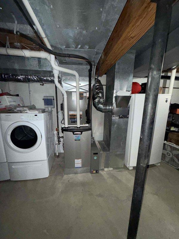 # HVAC Install - Complete System

Completed full HVAC system installation including 18 SEER heat pump outdoor unit and 99% AFUE gas furnace with air handler to serve main level and basement zones. Installed new furnace unit in basement mechanical room with proper clearances and ventilation requirements. Configured white PVC condensate drain lines with insulation wrap, routing vertically through ceiling joists to appropriate drainage location.

Connected silver flexible ductwork from furnace to existing distribution system, ensuring proper sealing and support. Mounted air handler component above furnace with metallic supply ductwork featuring elbow transitions for optimal airflow distribution. Installed black flexible return ductwork to complete air circulation loop. Positioned all equipment to maintain accessibility around existing laundry appliances and storage areas within the utility space.

Ran refrigerant lines between indoor and outdoor units with appropriate insulation and secur