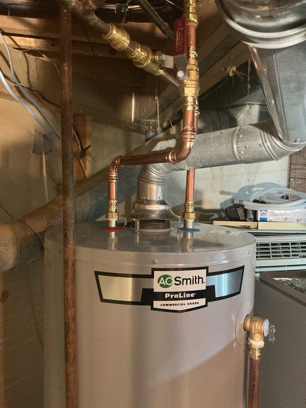 Installed AO Smith ProLine Commercial Grade 50-gallon gas water heater in basement utility room. Connected unit with copper piping, brass fittings, pressure relief valves, and shut-off valves with proper safety components including temperature and pressure relief valve piping.