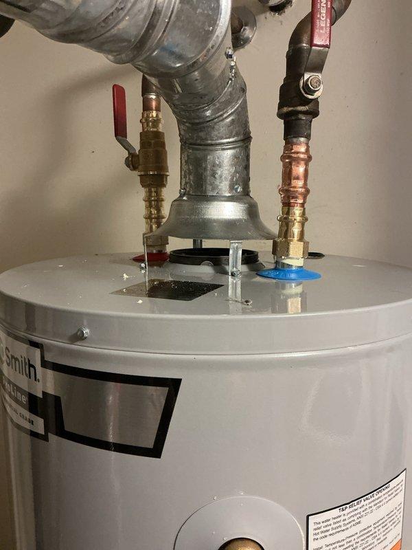 Completed installation of residential water heater in utility room with proper plumbing connections including copper and galvanized piping, pressure relief valve, shut-off valves with red handles, and flexible yellow gas line. All connections were secured with appropriate brass fittings and compression fittings, and the unit was installed adjacent to existing HVAC equipment with adequate clearance for service access and ventilation requirements.