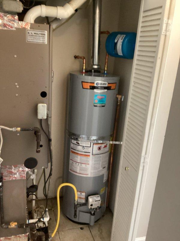 Installed a 40-gallon gas tall water heater (57 1/2" height x 21" width) in residential utility closet with proper venting through metallic exhaust flue. Connected hot and cold water supply lines using copper piping with brass fittings and shutoff valves, installed blue expansion tank on wall with appropriate piping connections, and ensured all plumbing connections met code requirements. Unit includes 6-year parts and 1-year labor warranty.