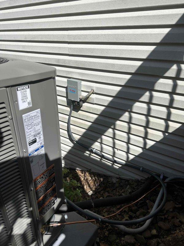 Completed installation of 3-ton, 19 SEER Lennox heat pump system with matching air handler at residential property. Unit positioned on concrete pad against exterior wall with proper clearances maintained, electrical disconnect mounted on siding with conduit run to condensing unit, and refrigerant lines routed and insulated per manufacturer specifications. System tested and operational upon completion.