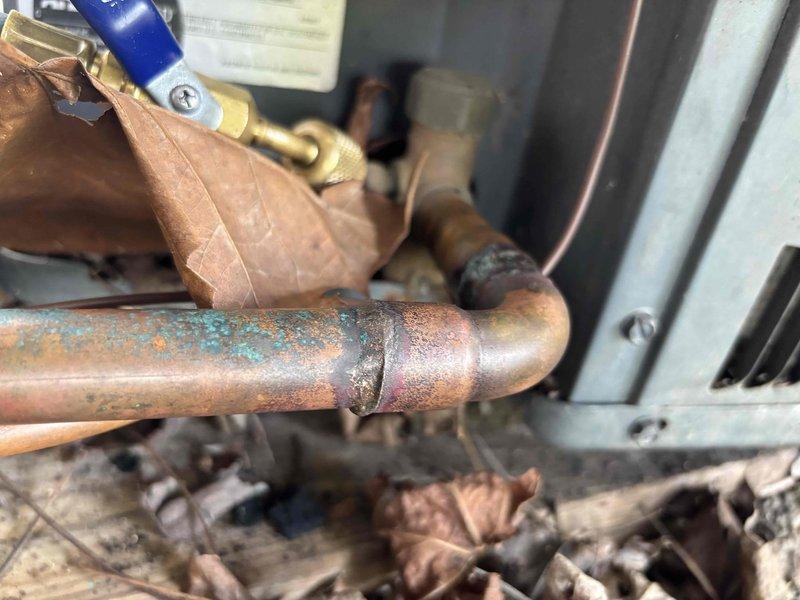 Completed follow-up repair on leaking refrigerant line joint on 10-year-old residential air conditioning system. Repaired corroded copper pipe connection that showed significant oxidation and patina formation on outdoor condensing unit. System restored to proper operation with adequate airflow confirmed at supply registers and refrigerant circuit integrity verified.