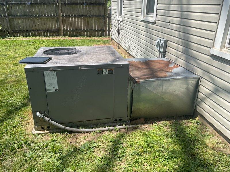 Conducted on-site assessment of residential cooling system damaged by fallen tree limbs. Evaluated packaged HVAC unit and associated ductwork/plenum for structural damage, operational integrity, and replacement requirements. Documented equipment condition showing weathering, surface oxidation, and impact damage to exterior components. Provided comprehensive replacement quote for complete system installation on existing concrete pad with necessary electrical and refrigerant line connections.