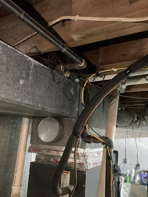 Conducted comprehensive on-site evaluation for tankless water heater conversion from existing electric tank water heater system. Performed detailed assessment of basement mechanical room infrastructure, including examination of current electrical service capacity, gas line availability, and venting requirements. Inspected existing plumbing configuration, noting vertical pipe runs and shutoff valve locations on concrete block foundation walls. Evaluated ceiling joist structure and available mounting locations for tankless unit installation. Assessed HVAC system proximity and clearance requirements for proper tankless water heater placement. Documented current water supply lines, drainage provisions, and electrical panel accessibility. Photographed mechanical room layout, pipe routing, and structural considerations to develop accurate conversion proposal. Reviewed ventilation options given basement window location and exterior wall access. Analyzed space constraints and utility infrastru
