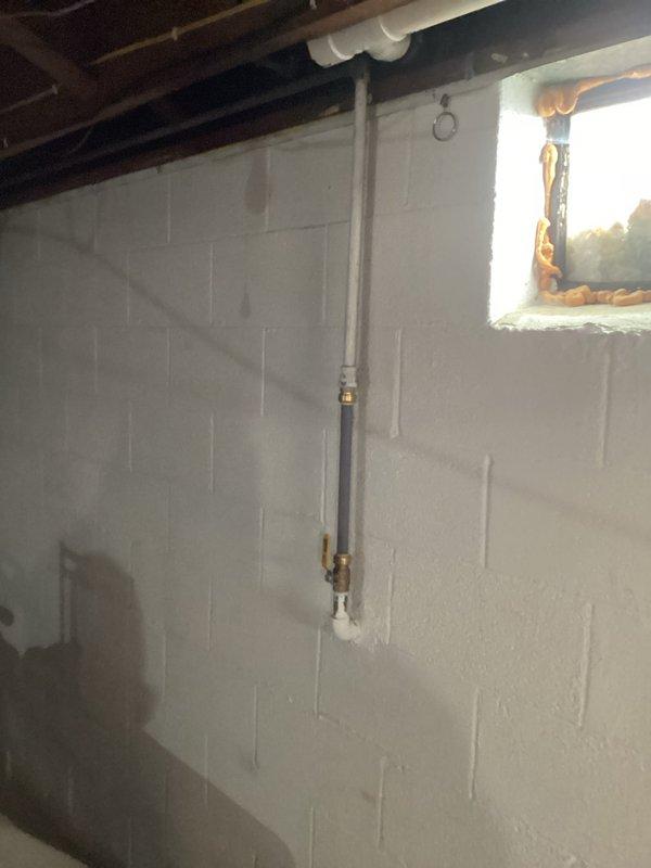 Conducted comprehensive on-site evaluation for tankless water heater conversion from existing electric tank water heater system. Performed detailed assessment of basement mechanical room infrastructure, including examination of current electrical service capacity, gas line availability, and venting requirements. Inspected existing plumbing configuration, noting vertical pipe runs and shutoff valve locations on concrete block foundation walls. Evaluated ceiling joist structure and available mounting locations for tankless unit installation. Assessed HVAC system proximity and clearance requirements for proper tankless water heater placement. Documented current water supply lines, drainage provisions, and electrical panel accessibility. Photographed mechanical room layout, pipe routing, and structural considerations to develop accurate conversion proposal. Reviewed ventilation options given basement window location and exterior wall access. Analyzed space constraints and utility infrastru