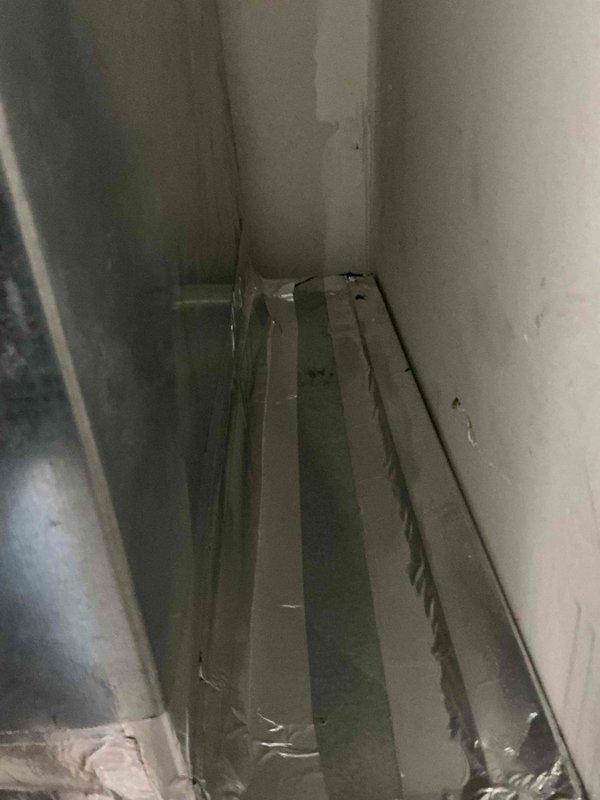 Completed follow-up site visit to inspect HVAC installation work in progress. Documented Carrier air handler unit properly positioned in mechanical closet with white PVC condensate drain lines installed vertically and horizontally from unit. Verified electrical control box mounted on wall with wiring connections in place. Photographed unfinished interior space showing exposed metal framing and ductwork requiring completion of remaining installation work.