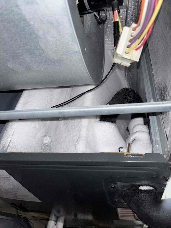 Responded to callback for HVAC system not operating following previous repair from 4/27. Upon inspection, discovered extensive frost and ice buildup throughout evaporator compartment and drain pan area, indicating restricted airflow or refrigerant issue causing coil to freeze. Inspected low-voltage control wiring at thermostat terminal connections, verifying proper wire terminations at C, G, and W1 terminals. System completely non-operational at time of arrival, requiring further diagnosis to determine root cause of recurring failure and excessive frost accumulation.