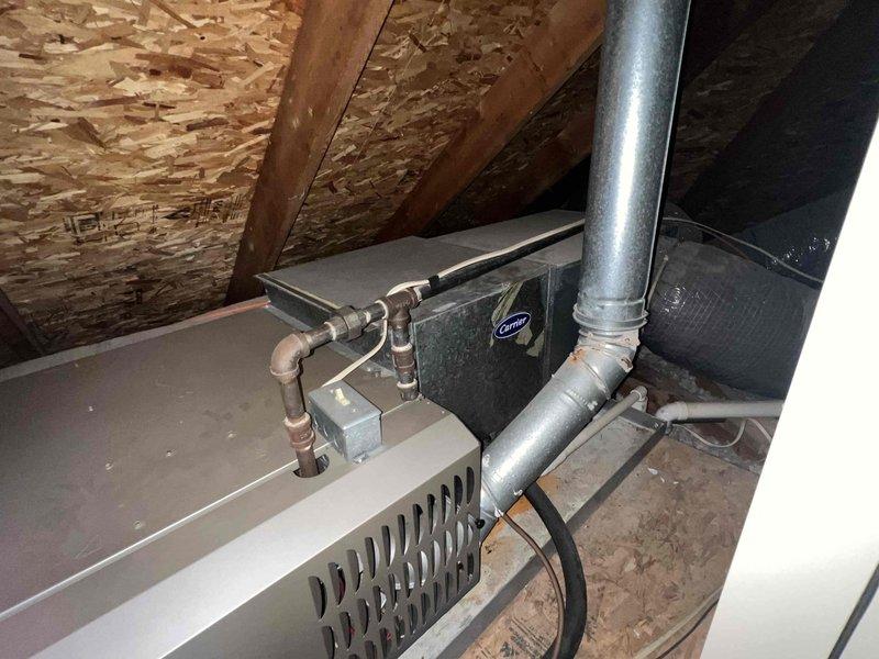 Completed HVAC replacement estimate for 22-year-old residential system located in attic space. Inspected existing Carrier brand air handler unit with associated refrigerant lines, ductwork, and attic installation configuration. Documented current equipment condition, including horizontal air handler positioning, copper refrigerant piping with multiple connections, metallic supply ductwork, and insulated flex duct runs throughout confined attic space. Assessed attic access, structural support adequacy, existing duct layout, and available clearances for replacement equipment installation. Photographed equipment labels, refrigerant line routing, duct connections, and overall mechanical system layout to prepare comprehensive replacement proposal. Provided information regarding promotional timing and confirmed homeowner availability requirements for future installation coordination.