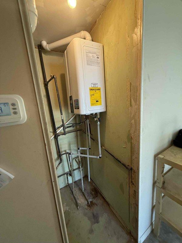 Successfully installed a 150-gallon capacity tankless water heater in residential utility closet. Completed full installation including gas line connections, water supply piping with copper and metal configurations, electrical hookup, and proper venting with white PVC exhaust system. Unit mounted securely to wall with all manufacturer specifications met and energy guide labeling in place. Installation coordinated with existing HVAC furnace system in shared mechanical room space, ensuring proper clearances and code compliance throughout.