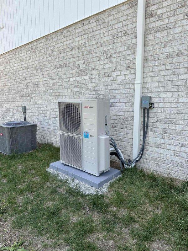 # HVAC Installation Summary

Successfully installed a 20,000 BTU dual-head ductless mini-split system at a residential property. Mounted one indoor air handler unit high on the interior wall near the ceiling in an upstairs room, positioned adjacent to a window for optimal air distribution. Installed the outdoor condenser unit on a concrete pad alongside existing HVAC equipment on the building's exterior. Ran refrigerant lines from the outdoor unit up the brick wall using white PVC line set cover for a clean, professional appearance. Connected electrical service with proper disconnect box mounted to exterior wall. System tested and confirmed operational upon completion.

# Detailed Work Performed

Completed installation of a dual-zone ductless mini-split heat pump system with 20,000 BTU capacity. The interior air handler was strategically mounted near the ceiling in a carpeted room with pale yellow walls, ensuring unobstructed airflow throughout the space. The unit placement considered 