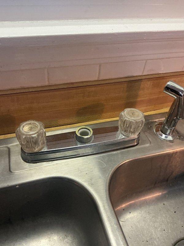 Completed installation of customer-supplied Delta Loraine kitchen faucet with double-handle assembly and pull-out spray head on existing double-basin stainless steel sink. Replaced exterior hose bib accessible from basement, installing new brass frost-free sillcock with ball valve shutoff. Both fixtures tested and verified operational with no leaks detected.