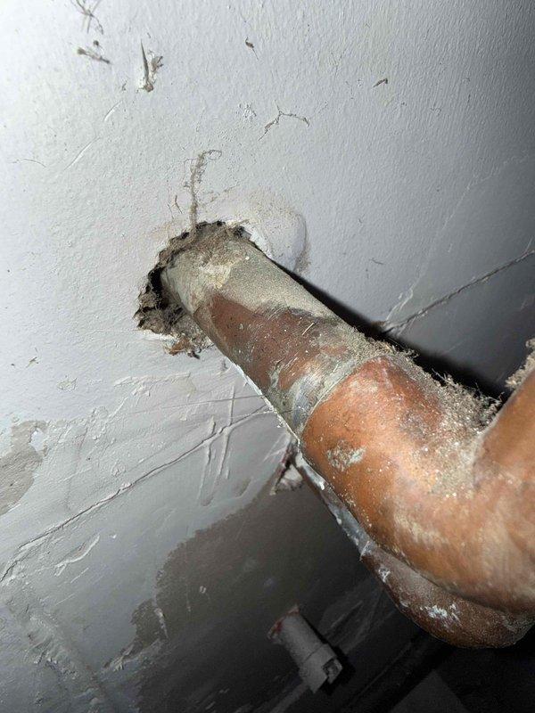 Responded to water leak call at residential property with 3-year-old HVAC system. Upon arrival, located active leak in garage area with significant water accumulation on floor. Inspected copper piping penetrating through wall and identified severe corrosion and oxidation on copper lines with characteristic greenish-white patina and mineral deposits indicating advanced deterioration. Observed water damage to surrounding wall surfaces with crumbling drywall material around pipe penetration points. Documented corroded copper piping conditions showing compromised integrity due to age and environmental exposure. Assessed leak source and extent of water intrusion affecting garage area.