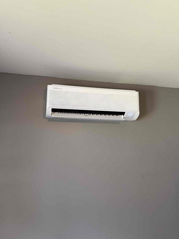 Completed installation of a 9000 BTU ductless mini-split system with single head configuration. The indoor Haier wall-mounted evaporator unit was installed on an interior gray wall near the ceiling, and the outdoor Lennox condenser unit was positioned on a concrete pad against the exterior of the home with proper refrigerant line connections, electrical disconnect, and conduit routing through the siding. System was tested and verified operational for both heating and cooling functions.