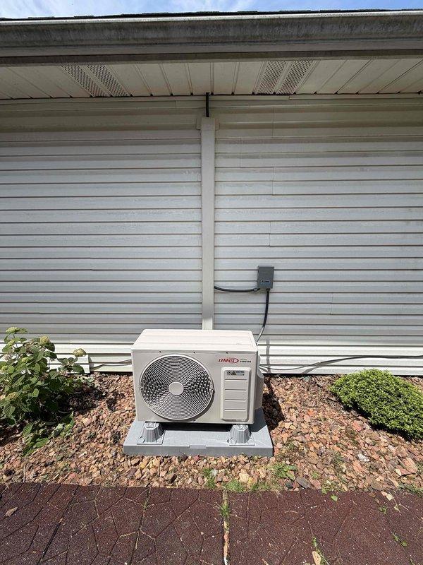 Completed installation of a 9000 BTU ductless mini-split system with single head configuration. The indoor Haier wall-mounted evaporator unit was installed on an interior gray wall near the ceiling, and the outdoor Lennox condenser unit was positioned on a concrete pad against the exterior of the home with proper refrigerant line connections, electrical disconnect, and conduit routing through the siding. System was tested and verified operational for both heating and cooling functions.