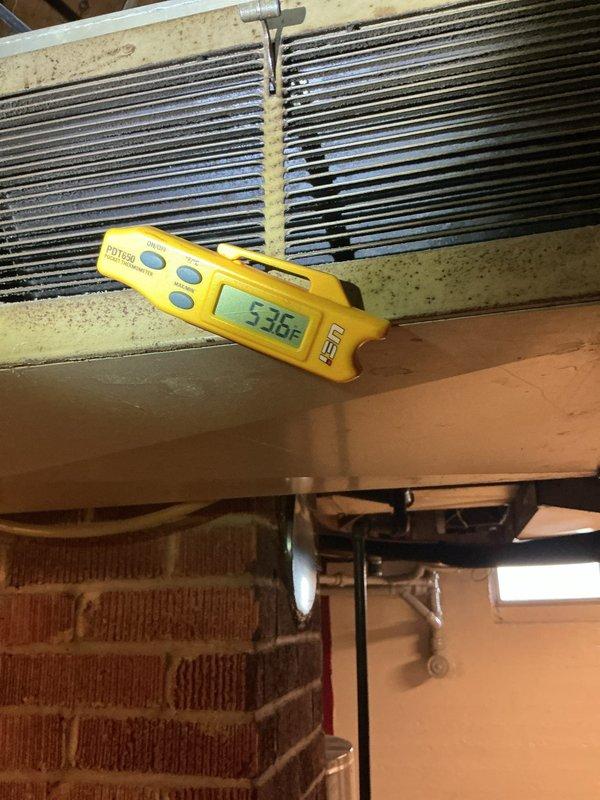 Responded to follow-up service call for incomplete HVAC work requiring system charging and furnace door switch replacement. Upon arrival, performed diagnostic temperature measurements on evaporator coil assembly using digital thermometer, recording supply air temperature of 53.6°F at the coil outlet. Documented current system operating conditions with thermal imaging to establish baseline performance metrics. Confirmed refrigerant charge is needed to achieve proper cooling capacity. Inspected furnace cabinet and verified door safety switch remains bypassed from previous service due to broken switch assembly. Photographed equipment conditions and measurement readings for service documentation. System requires return visit to complete refrigerant charging to manufacturer specifications and install replacement door interlock switch to restore proper safety controls on furnace unit.