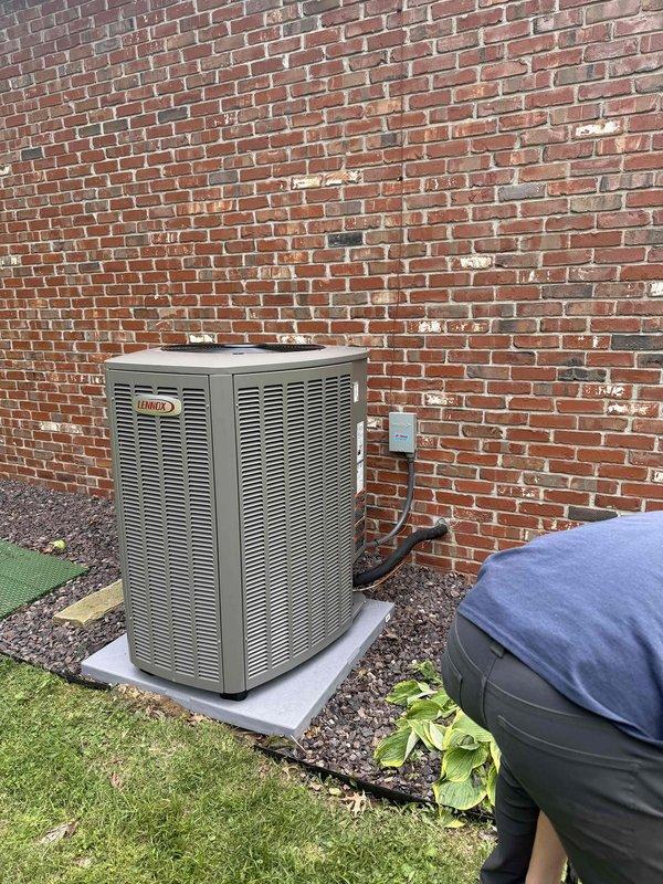 Completed installation of a 2-ton Lennox HVAC system including an 18 SEER air conditioning condenser unit and 97% AFUE upflow furnace. The outdoor condenser unit was positioned on a concrete pad against the building exterior with proper clearances maintained for optimal airflow and serviceability. All refrigerant lines were installed and the system was charged to manufacturer specifications, with pressure and temperature readings verified using digital diagnostic equipment to ensure proper operation. Electrical disconnect was mounted for safe system shutdown capability during future maintenance.