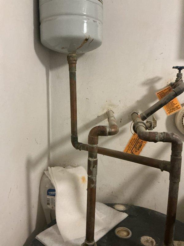 Responded to water leak reported above water heater in utility closet. Upon inspection, identified failed expansion tank with active leak at connection point on vertical copper supply line. Existing 2-gallon expansion tank showed significant corrosion and deterioration at threaded connection, causing water discharge onto surrounding piping and drain pan. Documented condition of corroded copper piping throughout assembly and noted multiple aged connections with heavy patina buildup. 

Ordered replacement 2-gallon expansion tank with female 3/4" pro press copper adapter for installation. System remains operational with water supply active. Scheduled follow-up installation appointment for next day upon part delivery. Estimated repair time of 45 minutes for tank replacement and connection. Advised customer of repair plan and timeline for completion.
