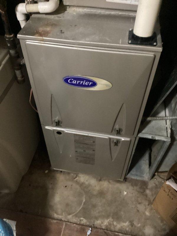 # Dismissed Visit - Single System HVAC Maintenance

Performed a dismissed visit on a single-system residential HVAC installation featuring a 10-year-old Carrier furnace unit. Conducted visual inspection of the vertical cabinet-style furnace located in the basement utility area. Documented equipment condition through photographic records showing the unit's exterior, access panels with black latches, manufacturer information labels, and associated PVC condensate drainage and venting piping at the top and side of the unit.

Verified the furnace cabinet integrity and noted the unit's clean, well-maintained white exterior finish with smooth metal construction. Observed proper installation on concrete flooring with appropriate clearances. Inspected visible piping components including white PVC lines extending horizontally and vertically from the top of the unit, as well as copper piping on the left side. Confirmed all access panels and fastening points were secure.

System specifications not