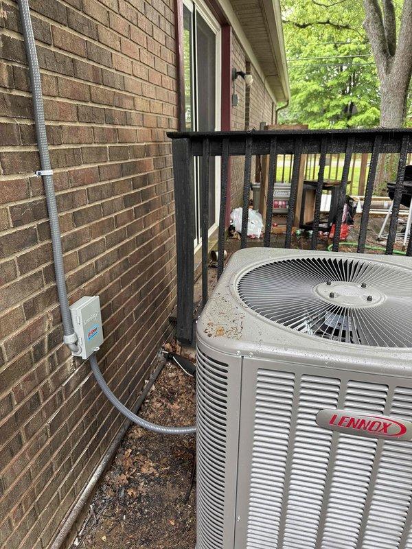 Completed installation of 2-ton, 15.5 SEER Lennox air conditioning system with matching evaporator coil at residential property in Chandler. New outdoor condensing unit was positioned on existing concrete pad on elevated deck adjacent to brick exterior, with gray electrical conduit and disconnect box properly mounted to exterior wall per code requirements. All serial numbers were documented photographically for warranty registration and service records.