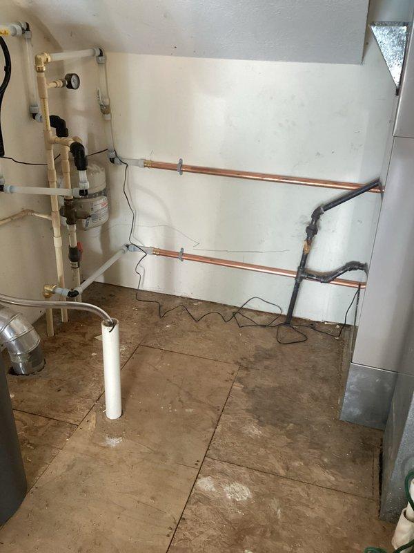 Completed installation of Energy Star-rated tankless water heater in interior utility room. Mounted unit to wall with proper structural support, connected copper supply and return lines with brass shutoff valves and fittings, and installed white PVC venting system routed through ceiling for proper exhaust ventilation. Wired electrical connections and control components to ensure safe operation. All plumbing connections tested and verified leak-free with proper water pressure and flow rates.