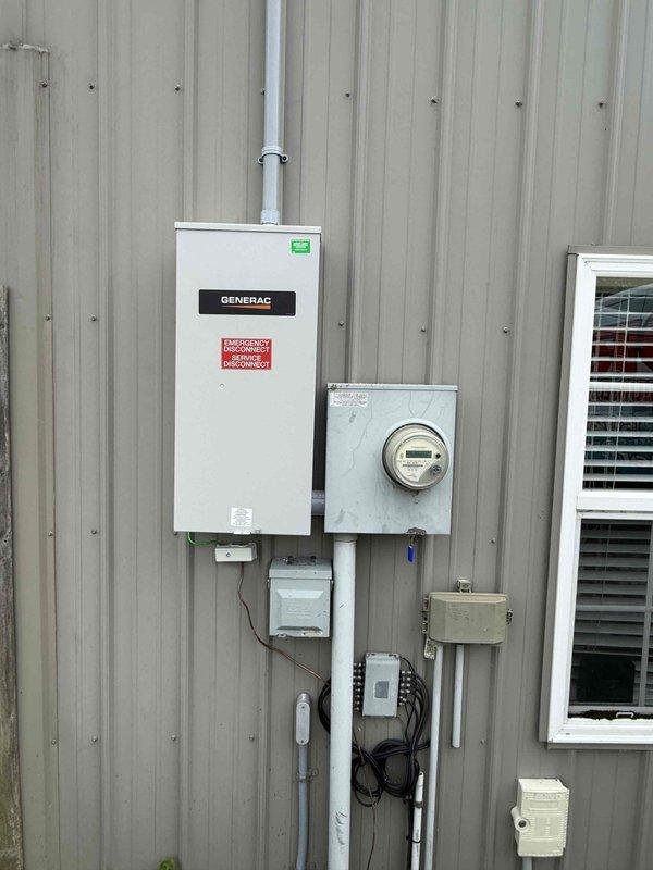 Completed follow-up site visit for Generac automatic transfer switch installation connected to Duke Power service. Documented existing electrical configuration including main service panel, utility meter, transfer switch with emergency power disconnect, and standby generator unit mounted on concrete pad. Verified proper installation of conduit runs, PVC piping, junction boxes, and all associated electrical components between the transfer switch enclosure and generator. Photographed complete system setup showing transfer switch with Generac branding, emergency disconnect labeling, generator unit positioning, and all interconnecting wiring and conduit pathways for service records.