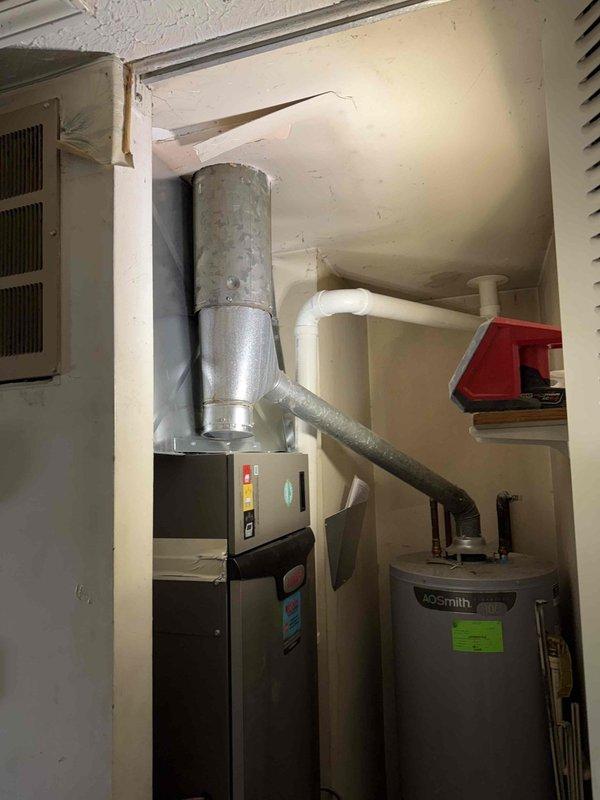 Completed installation of 2.5-ton, 15.5 SEER air conditioning system with 97% AFUE gas furnace in residential basement utility area. The new Lennox heating and cooling system was installed alongside existing water heater, with proper ductwork connections, condensate drainage routing via white PVC piping, and all required safety labeling in place. System was installed to manufacturer specifications with metallic supply duct trunk line extending from furnace cabinet to distribution points throughout the home.