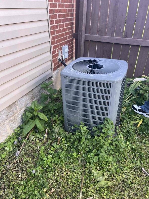 Responded to service call for complete central air conditioning system failure affecting entire residence. Assessed existing 1.5-ton (18,000 BTU) AC system of unknown age that had ceased operation. Inspected outdoor condenser unit, noting weathered housing with vegetation overgrowth around base and unit positioned on concrete pad against building exterior. Examined electrical disconnect box and verified circuit breaker panel configuration with dedicated AC circuit. Documented equipment condition through photography of both electrical panel and outdoor condenser unit. Provided consultation and prepared comprehensive replacement estimate for new HVAC system installation due to complete system failure and unknown equipment age.