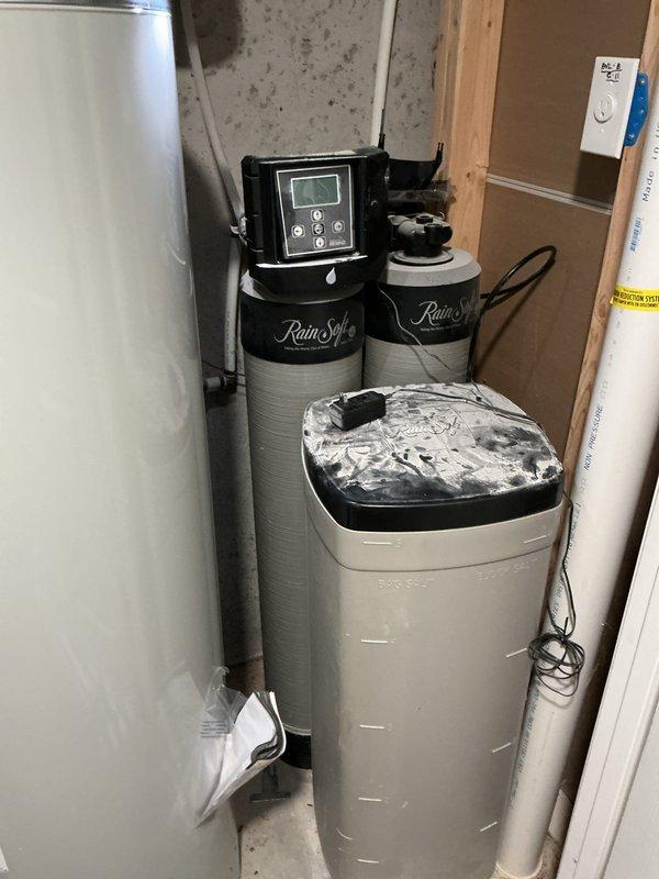 Responded to service call for RainSoft water softener system emitting strong odor. Upon arrival, inspected dual-tank water treatment system and brine tank. Removed contaminated salt from brine tank, which showed significant sediment and debris buildup at bottom causing malodorous conditions. Cleaned and sanitized brine tank interior, removing accumulated residue and organic matter. Refilled system with fresh water softener salt and verified proper operation of digital control head. Tested system cycling and confirmed elimination of odor issue. System restored to normal operating condition.