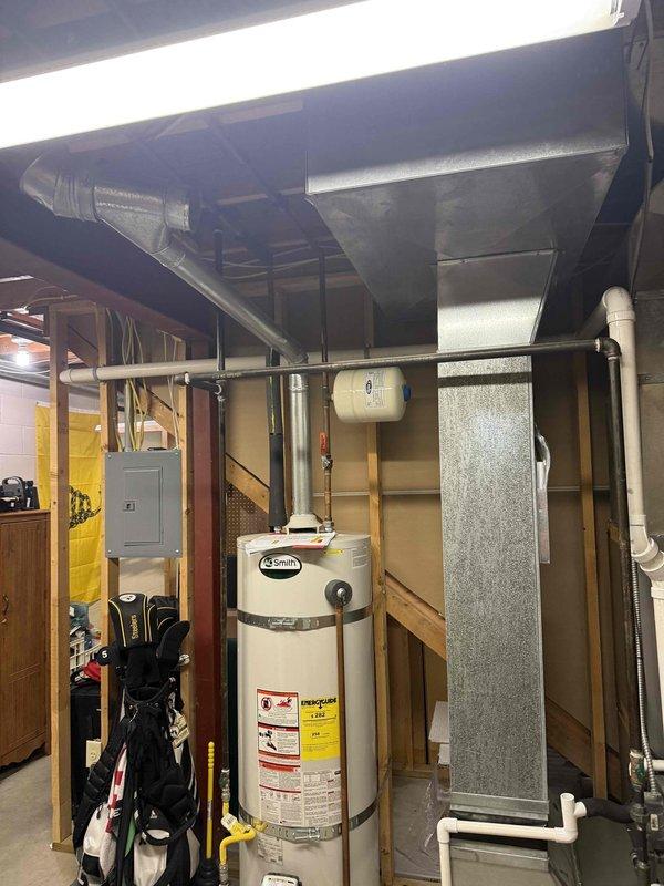 # HVAC System Installation

Completed full HVAC system installation in residential basement utility area, including 3-ton air conditioning unit with 18 SEER rating and 99% AFUE upflow furnace configuration. Installation included new ductwork routing throughout basement ceiling space, proper integration with existing infrastructure including water heater and electrical systems, and all necessary refrigerant lines and condensate drainage. System tested and verified operational upon completion.