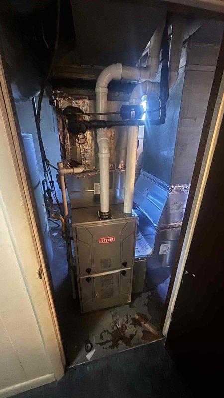 Conducted comprehensive replacement estimate for residential HVAC system including outdoor condenser unit and indoor Bryant furnace with integrated cooling components. Evaluated existing equipment condition, noting outdoor unit positioned on concrete pad with vegetation encroachment and indoor furnace installation in confined mechanical closet with PVC venting system and copper refrigerant lines. Documented system configuration, measured equipment dimensions, assessed electrical disconnect and ductwork connections, photographed current installation for replacement specifications, and provided homeowner with complete system replacement options during consultation.