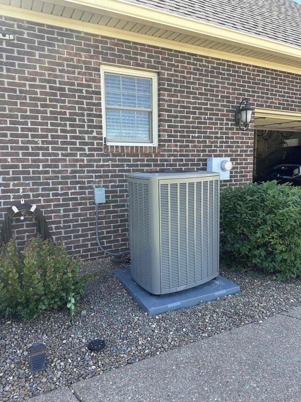 Completed full HVAC system installation featuring a 4-ton, 18 SEER Lennox air conditioning unit with 99% efficiency heating system. The outdoor condenser was professionally mounted on a concrete pad with gravel base against the brick foundation, with refrigerant lines and electrical conduits neatly routed vertically along the exterior wall to the roofline. All components were installed to manufacturer specifications, system was charged, tested, and verified operational.