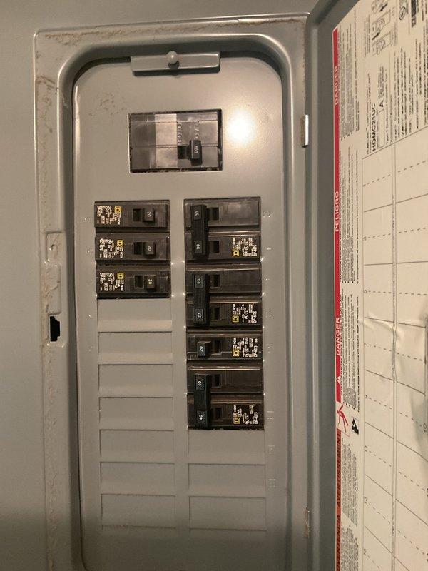 Completed comprehensive HVAC replacement estimate for residential property with 20-year-old existing system. Evaluated outdoor condensing unit positioned on concrete pad against exterior wall, noting copper refrigerant lines, electrical conduit routing, and wall-mounted disconnect box. Assessed electrical service panel configuration, verifying adequate breaker capacity and available expansion slots for potential new equipment installation requirements.