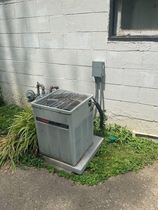 Completed comprehensive HVAC replacement estimate for residential property with 20-year-old existing system. Evaluated outdoor condensing unit positioned on concrete pad against exterior wall, noting copper refrigerant lines, electrical conduit routing, and wall-mounted disconnect box. Assessed electrical service panel configuration, verifying adequate breaker capacity and available expansion slots for potential new equipment installation requirements.