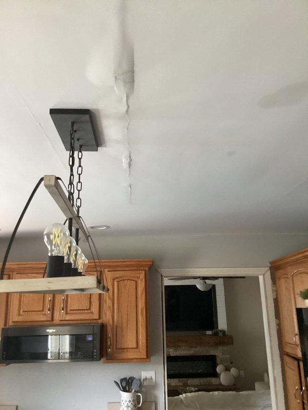 Responded to emergency water leak call for upstairs HVAC system (2 years old) actively dripping onto kitchen counters below. Upon inspection, discovered significant condensation accumulation on air handler drain pan and associated components in attic mechanical space. Identified clogged condensate drain line preventing proper drainage, causing overflow condition. Cleared blockage from primary drain line using appropriate tools and verified proper flow. Inspected secondary drain pan for damage and confirmed structural integrity. Tested system operation and monitored drain function to ensure leak was resolved. Documented moisture damage on kitchen ceiling showing visible crack along wall junction from water intrusion. Advised homeowner to monitor affected drywall area for further deterioration and recommended follow-up with contractor for cosmetic ceiling repairs once area fully dries. System returned to normal operation with proper condensate drainage restored.