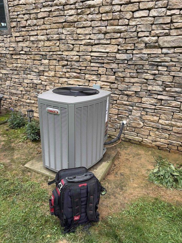 Completed installation of a 3-ton, 19 SEER Lennox heat pump system including outdoor condensing unit and indoor air handler. Outdoor unit was positioned on existing concrete pad against exterior stone wall with refrigerant lines properly routed and connected. Indoor air handler was installed with ductwork connections completed, filter access verified, and all electrical connections secured per manufacturer specifications.