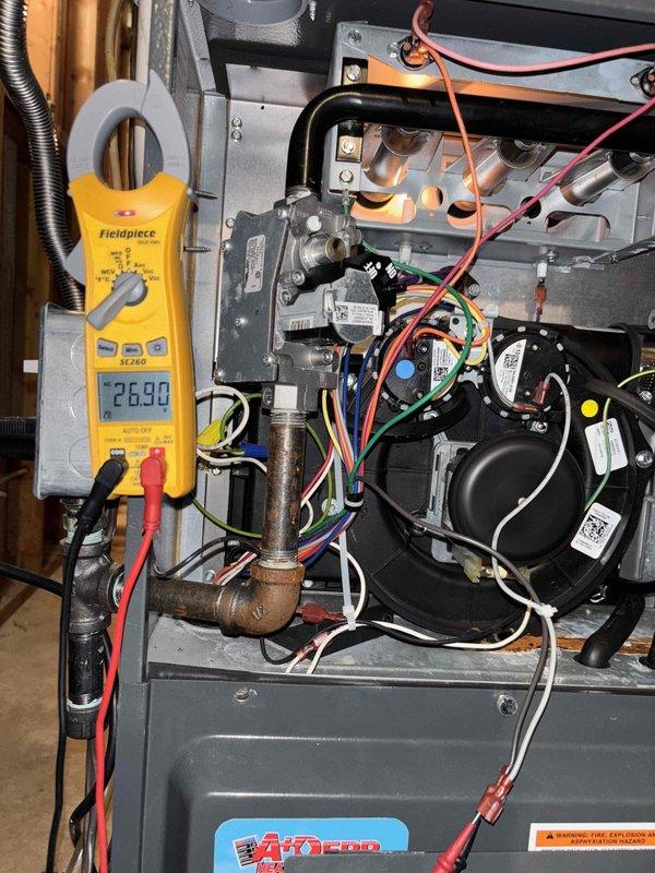 Responded to callback for heating system failure following planned maintenance visit. Upon arrival, confirmed no heat operation with thermostat set to 72°F and indoor temperature at 69°F. Performed diagnostic testing on Amana furnace system using Fieldpiece clamp meter to verify electrical parameters and component functionality. Inspected gas valve assembly, pressure switch connections, and control board wiring. Measured amp draw at 26.00 amps during testing cycle. Examined all electrical connections including orange, red, white, green, blue, and yellow wire terminals for proper seating and continuity. Verified gas valve operation, checked ON/OFF positioning, and confirmed pressure gauge readings within manufacturer specifications. Restored heating operation to system and cycled unit multiple times to ensure reliable startup and proper temperature rise across heat exchanger. System now operating normally with thermostat calling for heat and unit responding appropriately.