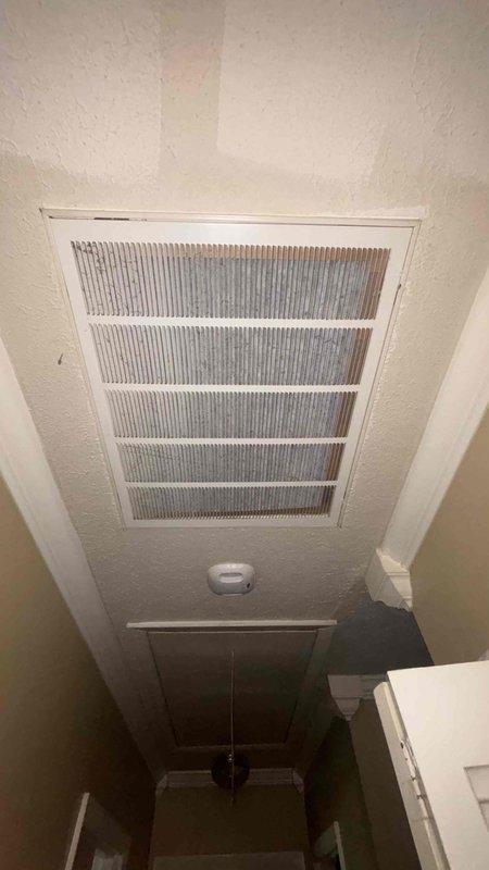 Conducted comprehensive replacement estimate for aging HVAC system including 25-year-old furnace and older air conditioning unit. System currently operational but nearing end of service life. Documented existing equipment configuration including ceiling-mounted return air vent showing significant dust accumulation and digital thermostat displaying heat mode operation at 74 degrees.
