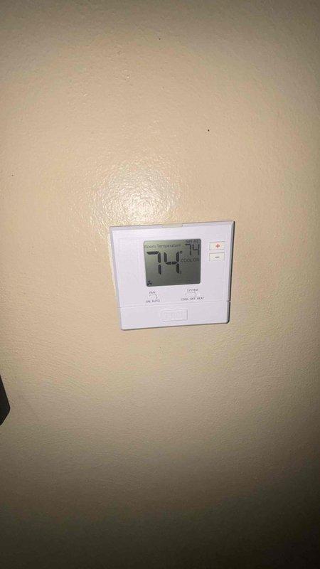 Conducted comprehensive replacement estimate for aging HVAC system including 25-year-old furnace and older air conditioning unit. System currently operational but nearing end of service life. Documented existing equipment configuration including ceiling-mounted return air vent showing significant dust accumulation and digital thermostat displaying heat mode operation at 74 degrees.